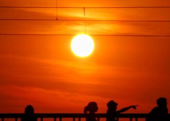 silhouettes of people on a bridge at sunset